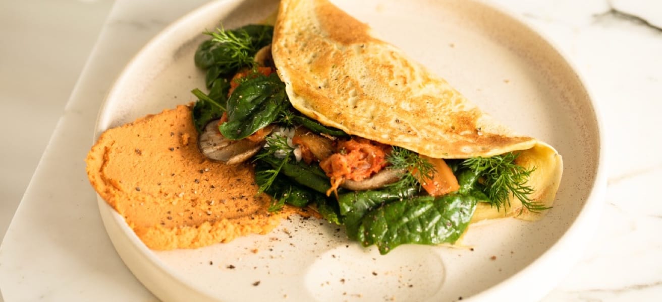 Golden omelet on a white plate, with fresh herbs around. Flavor and simplicity in every bite.